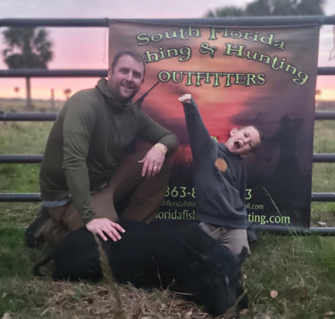 Father and son celebrate a successful wild hog hunting trip in South Florida